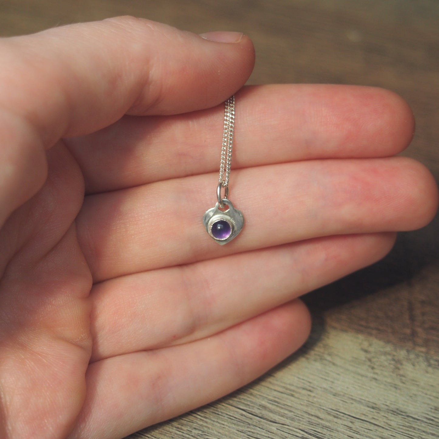 collier-pour-femme-en-argent-cœur-en-améthyste sur une main