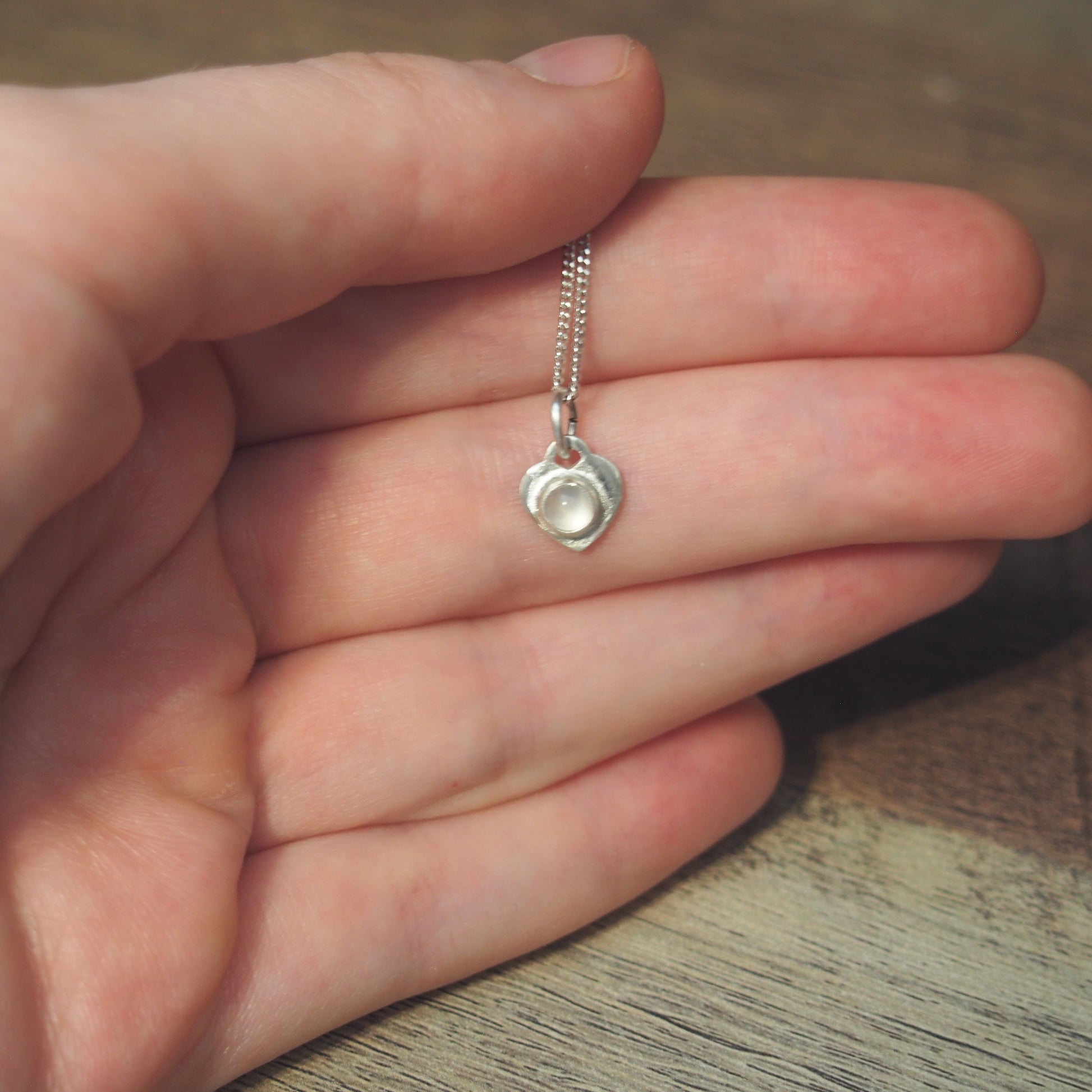 collier pour femme en argent cœur en quartz rose sur une main