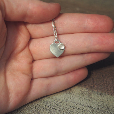 collier pour femme en argent cœur en quartz rose naturel sur une main