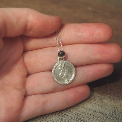 collier pour femme en argent fleur de cerisier en quartz fumé sur une main