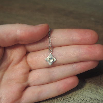 collier pour femme en argent fleur en quartz blanche sur une main