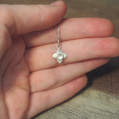 collier pour femme en argent fleur en quartz rose naturel sur une main