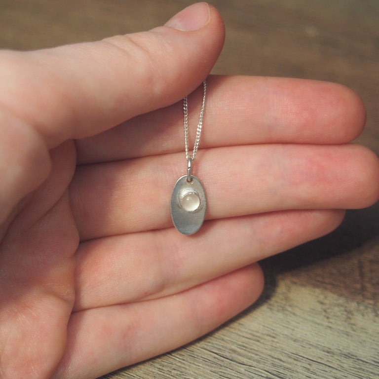 collier pour femme en argent oval en quartz rose sur une main