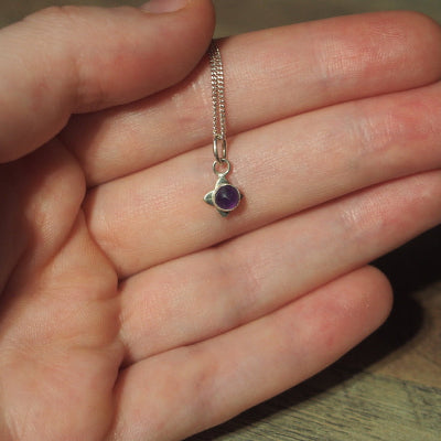 collier pour femme en argent petite fleur en améthyste sur une main