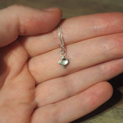 collier pour femme en argent petite fleur en quartz blanc sur une main