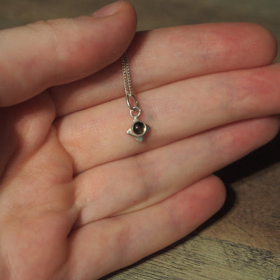collier pour femme en argent petite fleur en quartz fumé sur une main