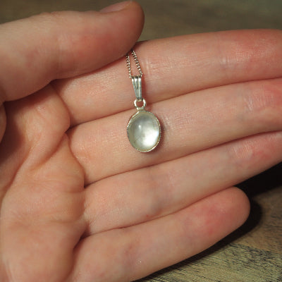 collier pour femme en argent pierre quartz blanc et coquillage sur une main