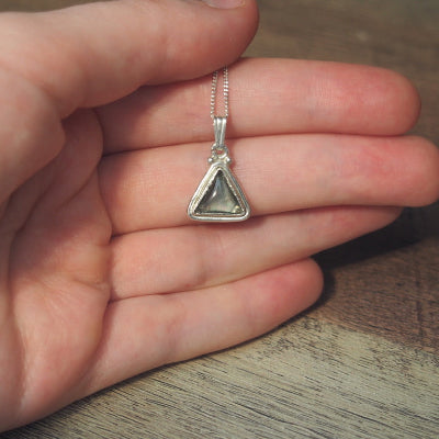 collier pour femme en argent triangle en quartz blanc et coquillage sur une main